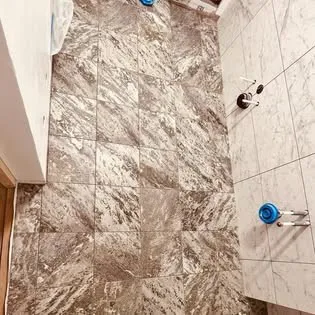 Badrumsgolv och vägg med stora marmorliknande klinkerplattor